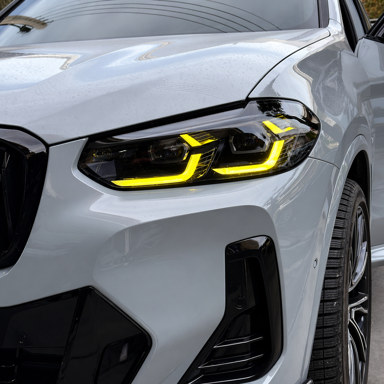 Close-up of a BMW X3/X4 headlight with a yellow DRL headlight
