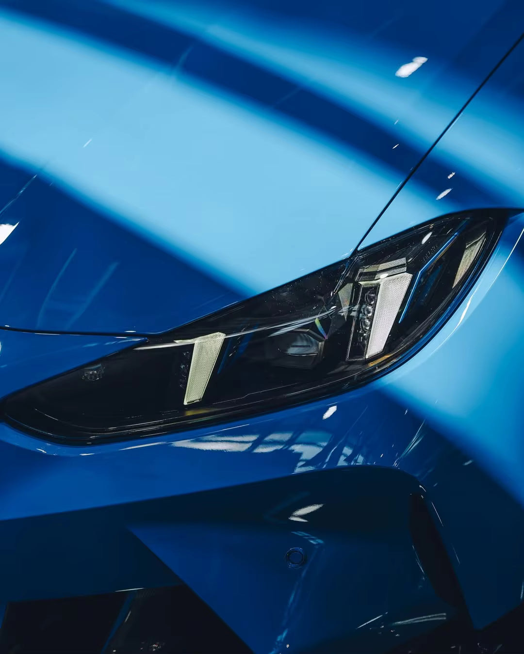 Close-up of a blue car's headlight with a blurred background